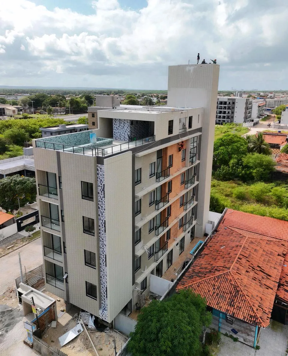 Vista aérea do mesmo edifício residencial em fase final de obra, com piscina na cobertura